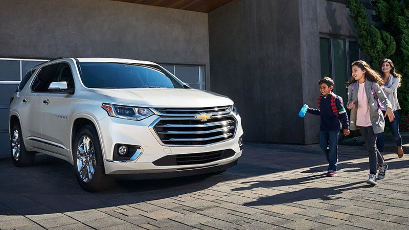 Kids running in front of a Chevrolet Traverse parked in front of a home.
