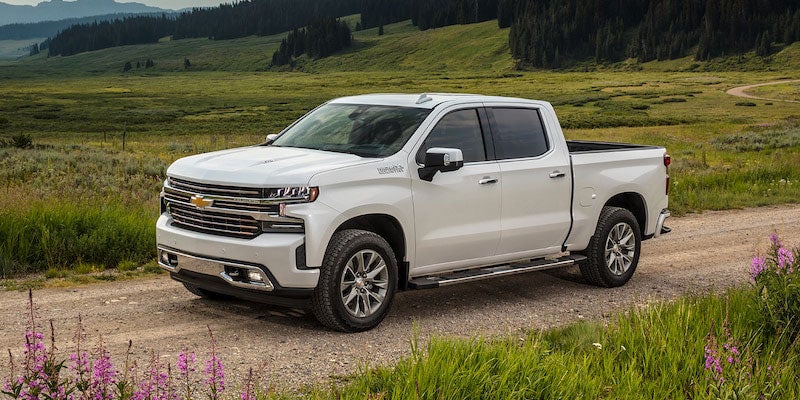Chevrolet Silverado 1500 driving on a road with lush green grass on either side.