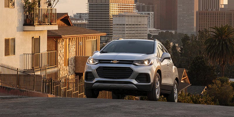 Chevrolet Trax driving on a road with buildings in the background.